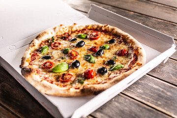 Pizza in a cardboard box on table ready to customer.