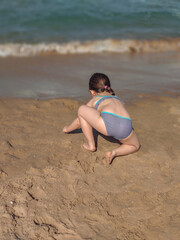 Girl playing with the sand on the beach