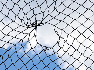 Black Netting with a Hole against a Cloudy Blue Sky