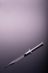 Syringe on glossy black background.  Dark side of Immunization, vaccination, or drugs and darkness conmcept.