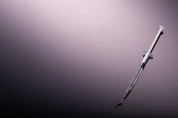 Syringe on glossy black background.  Dark side of Immunization, vaccination, or drugs and darkness conmcept.