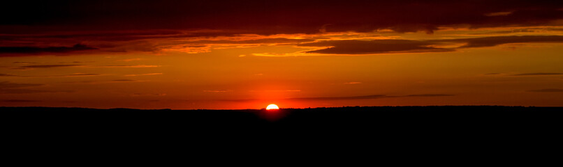 The sky and clouds are illuminated by the setting sun. Panorama.