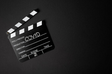 Fototapeta na wymiar Movie clapperboard during the second wave of the coronavirus pandemic on a black background. Covid concept.