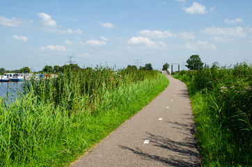 Kinderdijk, The Netherlands, August 2019. A small road winds through the Dutch countryside, lined with very green grass. Beautiful sunny day