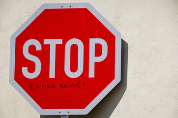 Stop sign with inscription Eating Bacon
