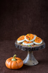 Fall harvest, orange frosted sugar cookies with colorful sprinkles, on a wooden cake stand, orange ceramic pumpkin
