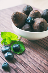 Closeup chocolate truffles with blueberry and mint on wooden background