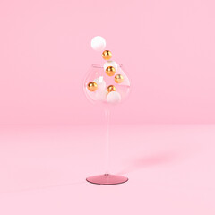 christmas concept, glass with balls on pink background, copy space