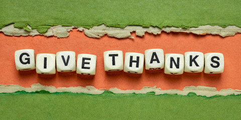 give thanks text in wooden letter cubes against abstract green and orange handmade paper banner, Thanksgiving concept