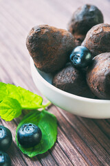 Closeup chocolate truffles with blueberry and mint on wooden background