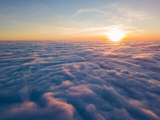 Fototapeta premium Sunset over curly clouds, aerial high flight. The last rays of the sun shine on the clouds.
