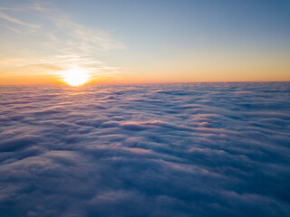 Obraz premium Sunset over curly clouds, aerial high flight. The last rays of the sun shine on the clouds.