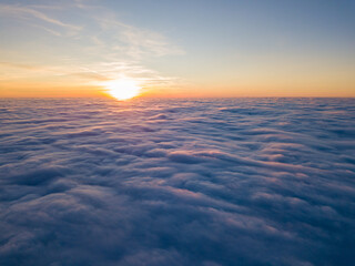 Fototapeta premium Sunset over curly clouds, aerial high flight. The last rays of the sun shine on the clouds.