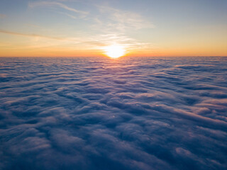 Sunset over curly clouds, aerial high flight. The last rays of the sun shine on the clouds.