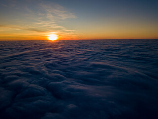 Fototapeta na wymiar Sunset over curly clouds, aerial high flight. The last rays of the sun shine on the clouds.