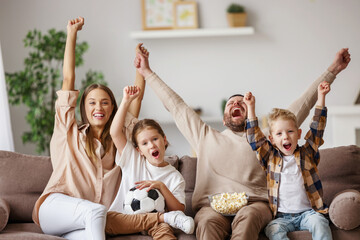 Excited family watching football at home
