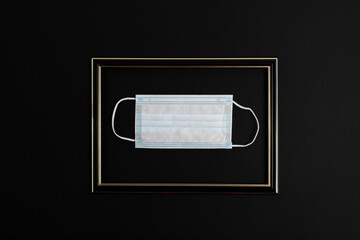 Flat lay medical mask in a frame on a black background as an exhibit in a museum. Capture 2020 in...