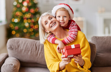 Cheerful child congratulating grandmother at Christmas