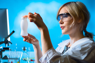 Probiotic yogurt. Laboratory assistant holds a white bottle in her hands. Biologist in lab examines...