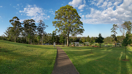 Beautiful view of a park with green grass and tall trees and deep blue sky with light clouds in the background, Heritage park, Castle Hill, Sydney, New South Wales, Australia
