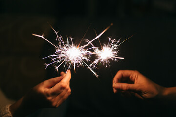 Burning New Year sparkler. Bengal light scattering into small sparkles. Celebrating christmas and new year 2021