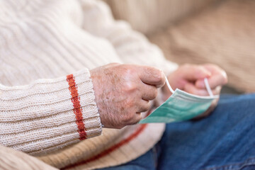 Close up view, of Senior man hands putting face mask against coronavirus . High quality photo