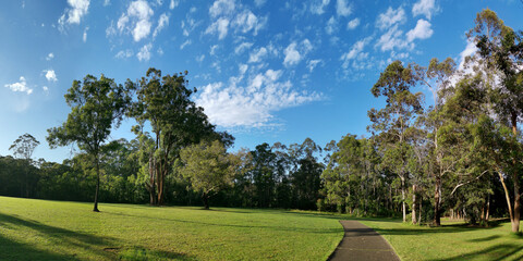 Beautiful panoramic view of a park with green grass and tall trees and deep blue sky with light clouds in the background, Heritage park, Castle Hill, Sydney, New South Wales, Australia
