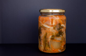 Jar of Kimchi, typical Korean food made with Korean cabbage and spices on black, white background.