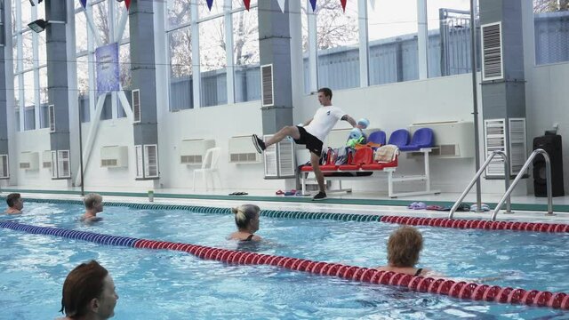 Instructor training women aqua gymnastic in swimming pool.