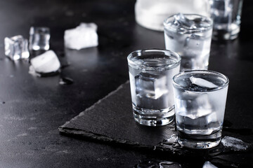 Frozen Vodka in shot glasses on black background, iced strong drink