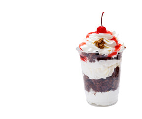 Dessert of cream, sponge cake, cherries and nuts in a plastic Cup on an isolated background. Copy space