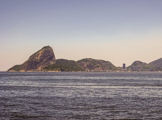 Niteroi, Brazil - December 24, 2008: Sugarloaf hill seen from Gragoata coastal neighborhood accross the Guanabara bay. under light blue late afternoon sky.