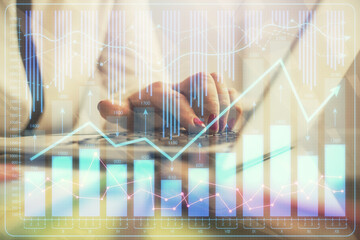 Double exposure of businesswoman hands typing on computer and financial graph hologram drawing....
