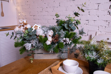 Interior light kitchen with christmas decor and tree. White kitchen set. Wooden table. Loft style kitchen with white brick.  New Year.