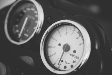 Motorcycle gauges and tachometer. RPM gauge photographed from close on the bike. Black and white photo.