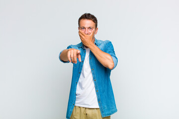 young handsome man laughing at you, pointing to camera and making fun of or mocking you