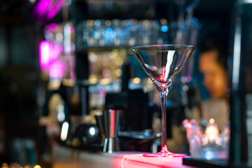 Bartender preparing tasty mixed tasty alcoholic drink in empty martini cocktail glass on bar counter for customer in nightclub. Celebration party, nightlife business and alcohol addiction concept