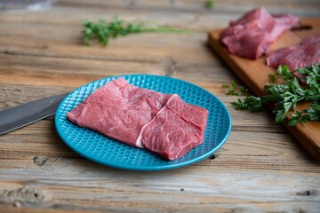 Raw beef on wooden table and on a blue plate