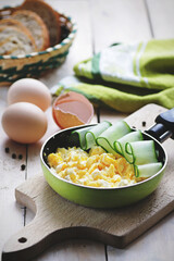 Scrambled eggs with cucumber in pan