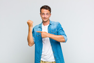 young handsome man looking impatient and angry, pointing at watch, asking for punctuality, wants to...