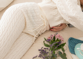 Woman dressed on a comfortable wool loungewear laid on bed.