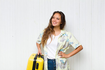 young hispanic woman smiling happily and daydreaming or doubting, looking to the side