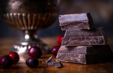 Thick pieces of chocolate and berries on dark background