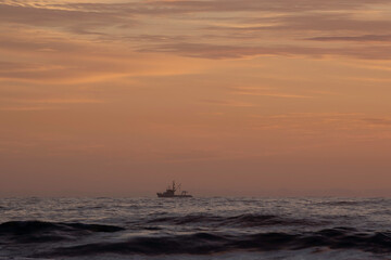 Fototapeta na wymiar A boat on the hozizon at Sunrise at Turimetta Beach