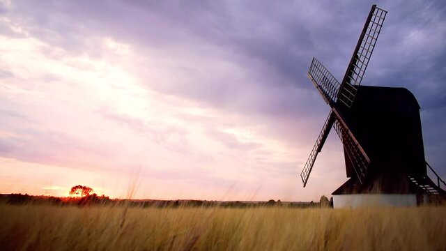 Stunning sunset landscape view for Pitstone Windmill with dramatic cloudy sky and beautiful colors of sun setting in red and orange