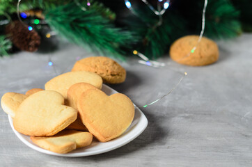 Homemade cookies in the shape of a heart in a white plate  on the background of Christmas decorations.