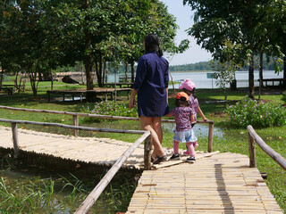 A mother walking on a bamboo wooden pavement along with her two little baby girls - spending time outdoor with your children