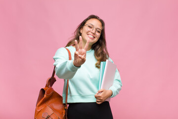 young hispanic woman smiling and looking friendly, showing number three or third with hand forward,...