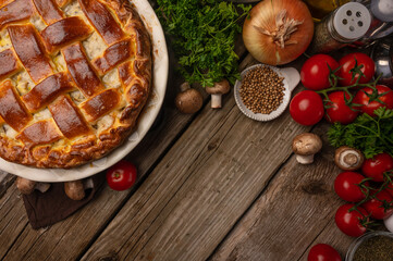 Ruddy meat pie on wooden table with variety of ingredients background. Concept of cooking process. Backstage of preparing tasty meal. View from above. Flat lay. Recipe book. Space for text.