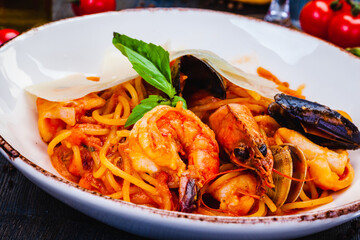 Pasta with seafood, tomato and parmesan cheese on white  plate